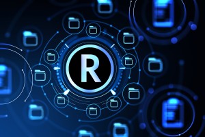 The Trademark symbol on digital electronic blue background with floating icons of file folders.